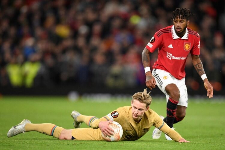 Gelandang FC Barcelona Frenkie de Jong memegang bola setelah dilanggar gelandang Manchester United Fred di Old Trafford Jumat (24/2/2023).
